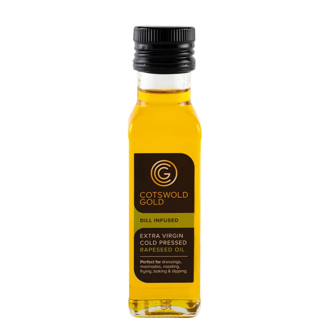 A bottle of Cotswold Gold Dill Infused Rapeseed Oil, featuring a clear glass bottle filled with golden-yellow oil, a black cap, and a dark brown label with gold lettering, set against a plain white background.